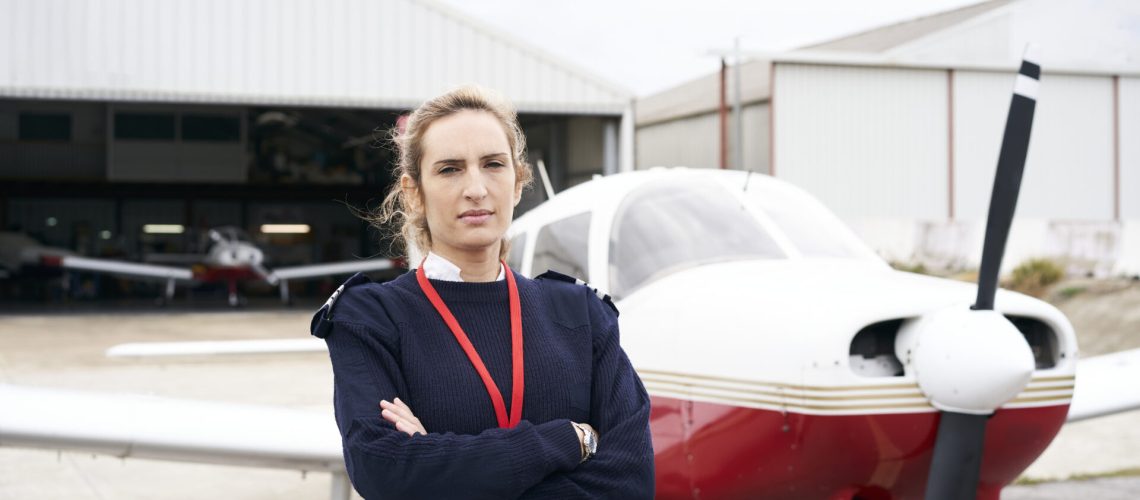 Young female pilot posing in front of her plane.